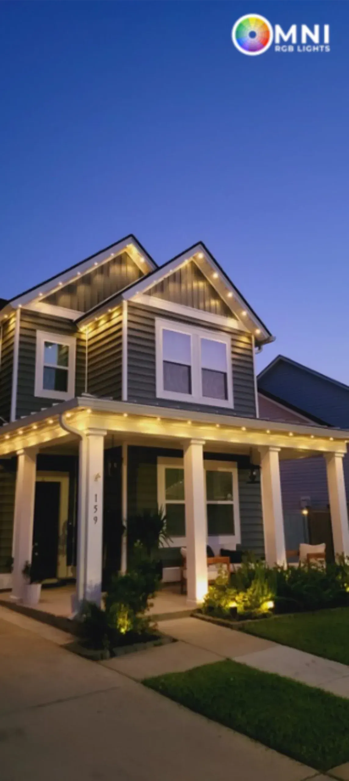 Two-story house with warm exterior lights at dusk, featuring a covered porch and peaked roof.