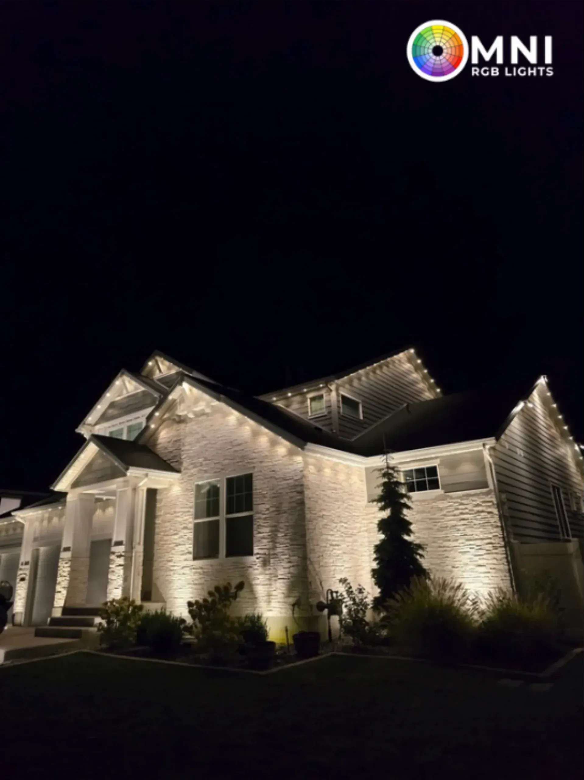 Night-lit white brick house with warm exterior lighting and dark sky.