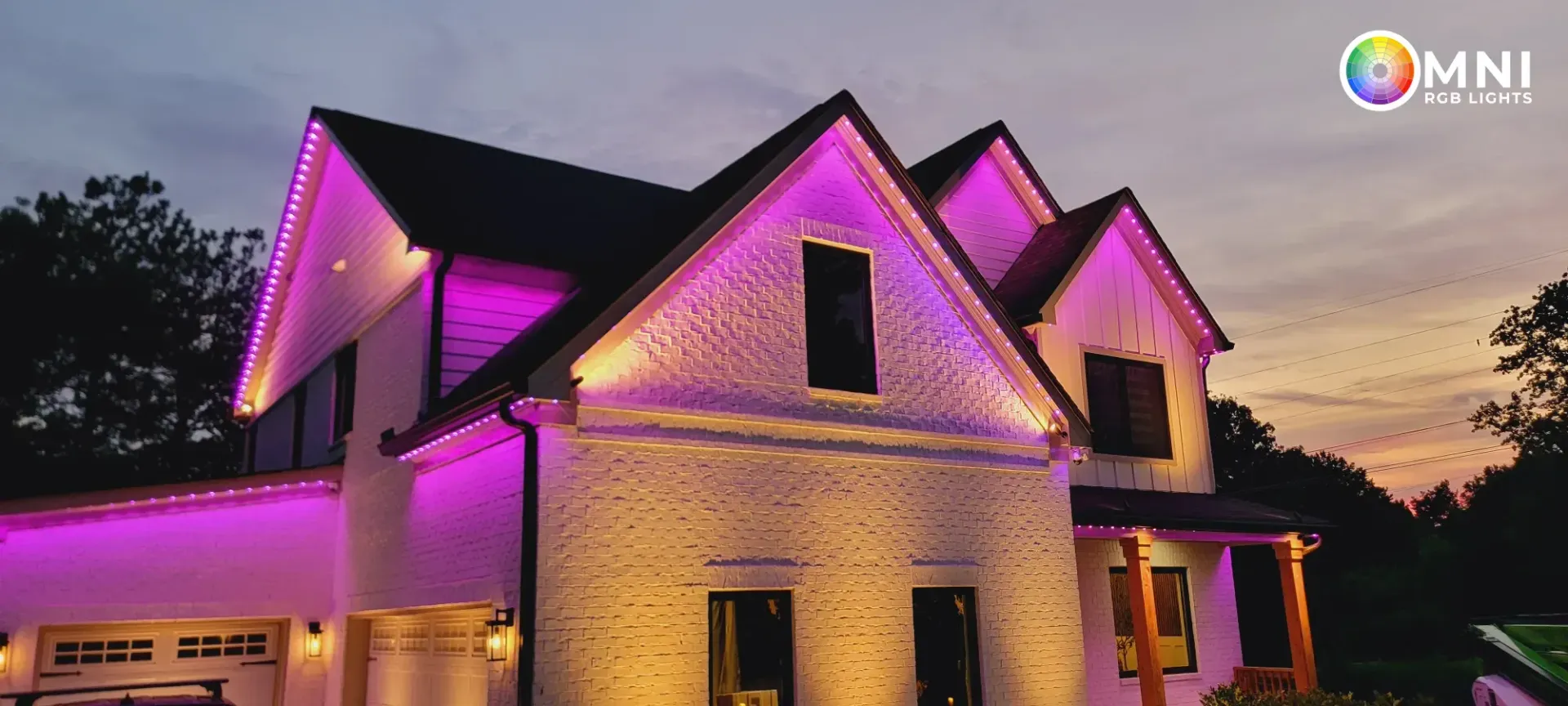 Two-story house at dusk with purple accent lighting and a warm-lit garage