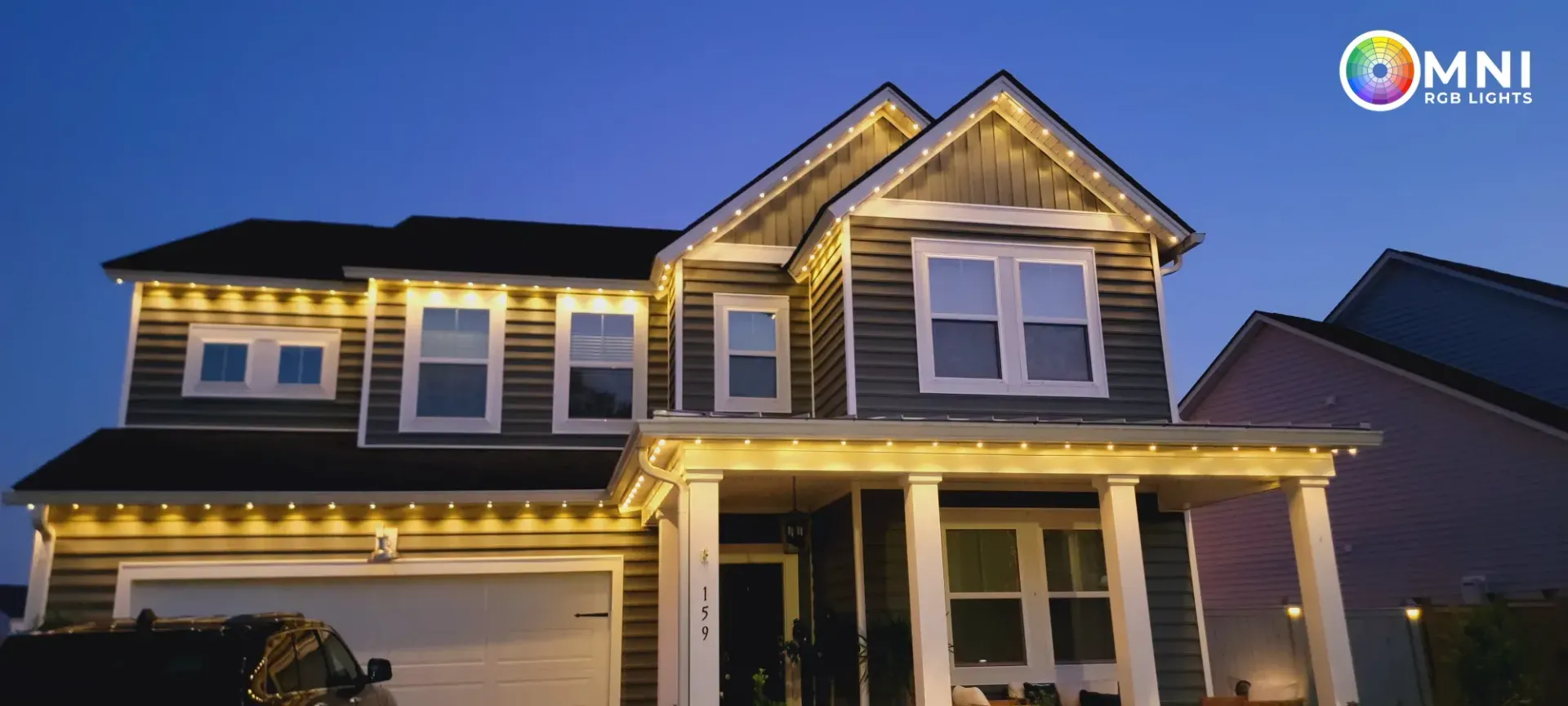 Two-story house at dusk with warm porch lights and a garage