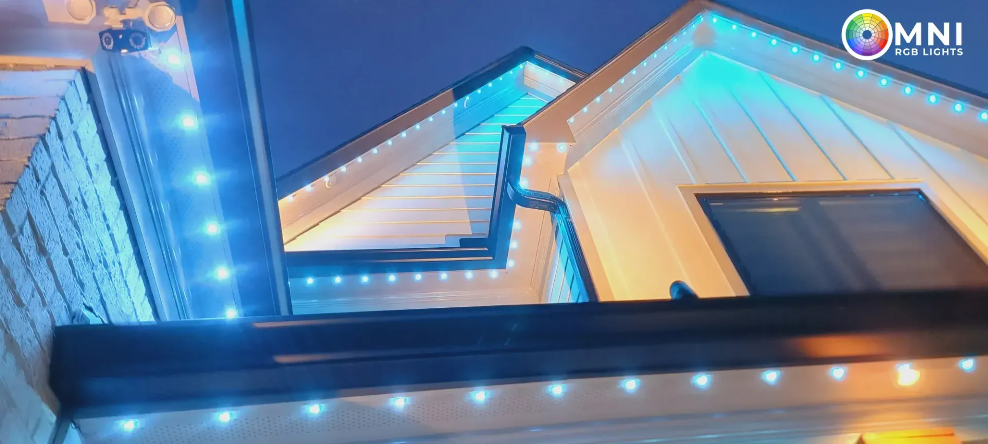 Blue-lit modern building facade at night with warm interior lights and lit roof edges