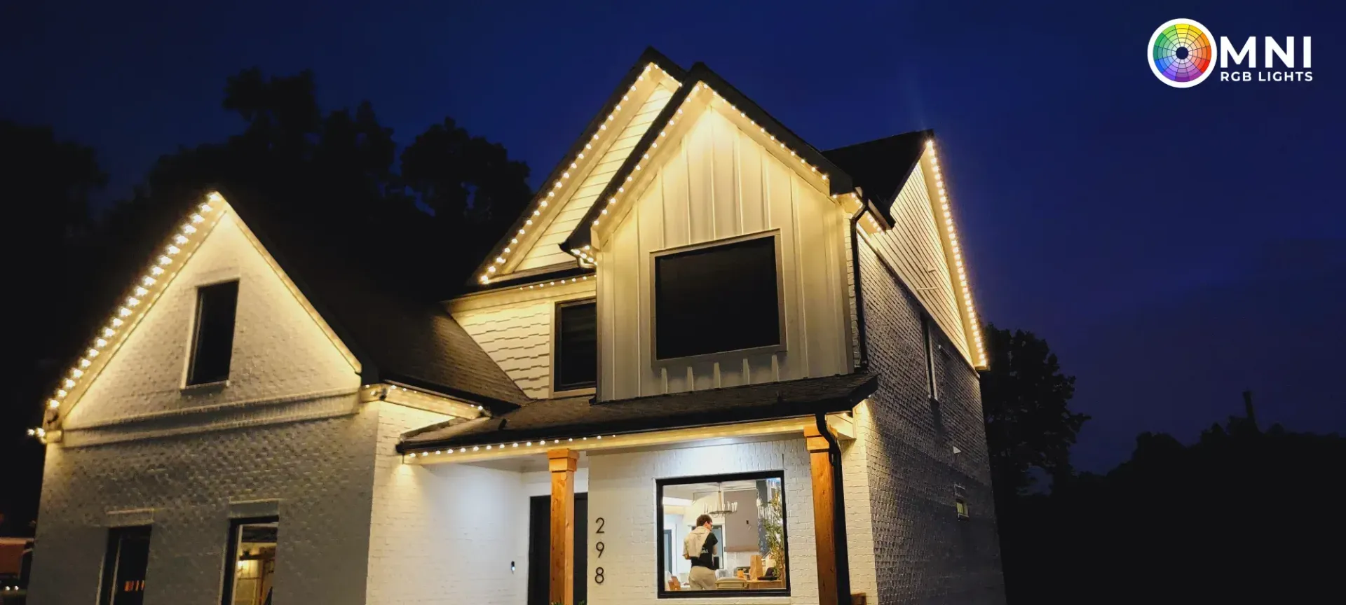 Illuminated house at night with steep gabled roof and warm lights under a dark sky