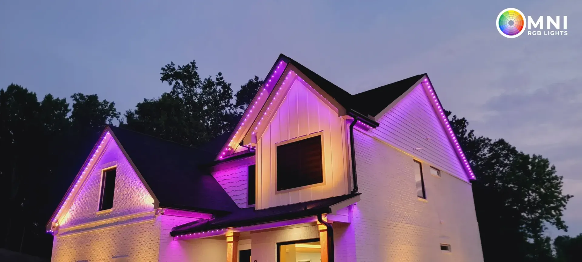 House exterior lit with purple and white lights at dusk under a dark sky