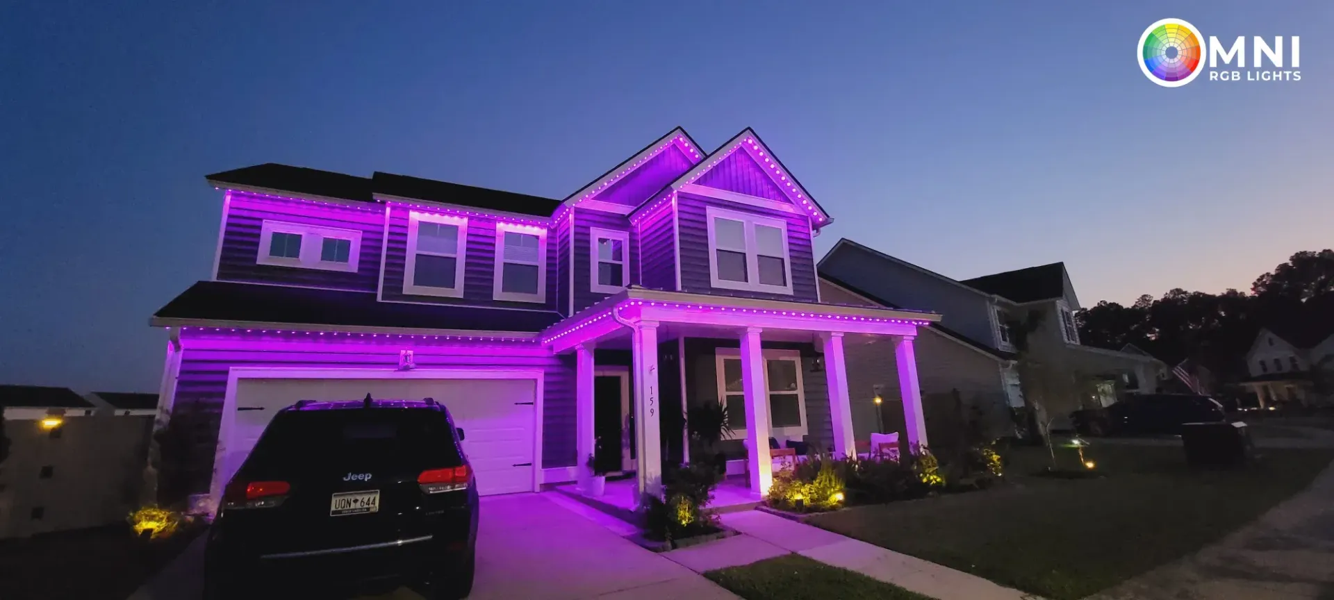 House lit in bright purple at night with a car in the driveway