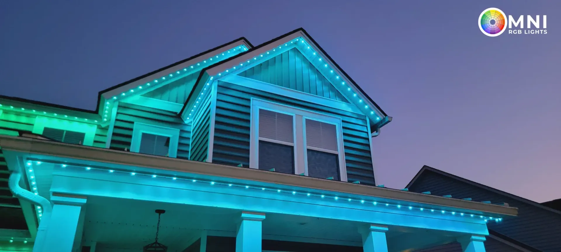 Blue-lit house exterior at dusk with illuminated roofline and porch