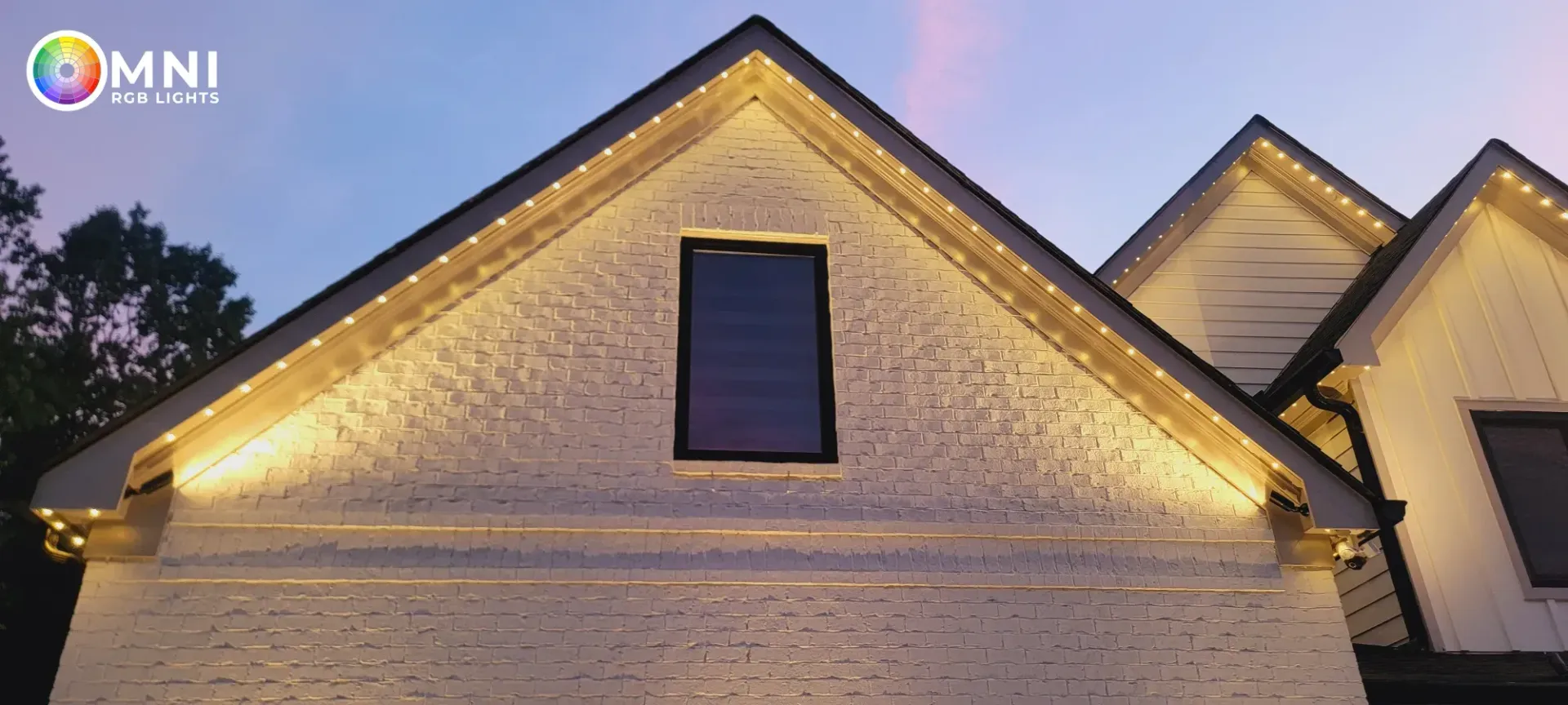 Lit stone house gables at dusk, with warm exterior lighting and dark windows.