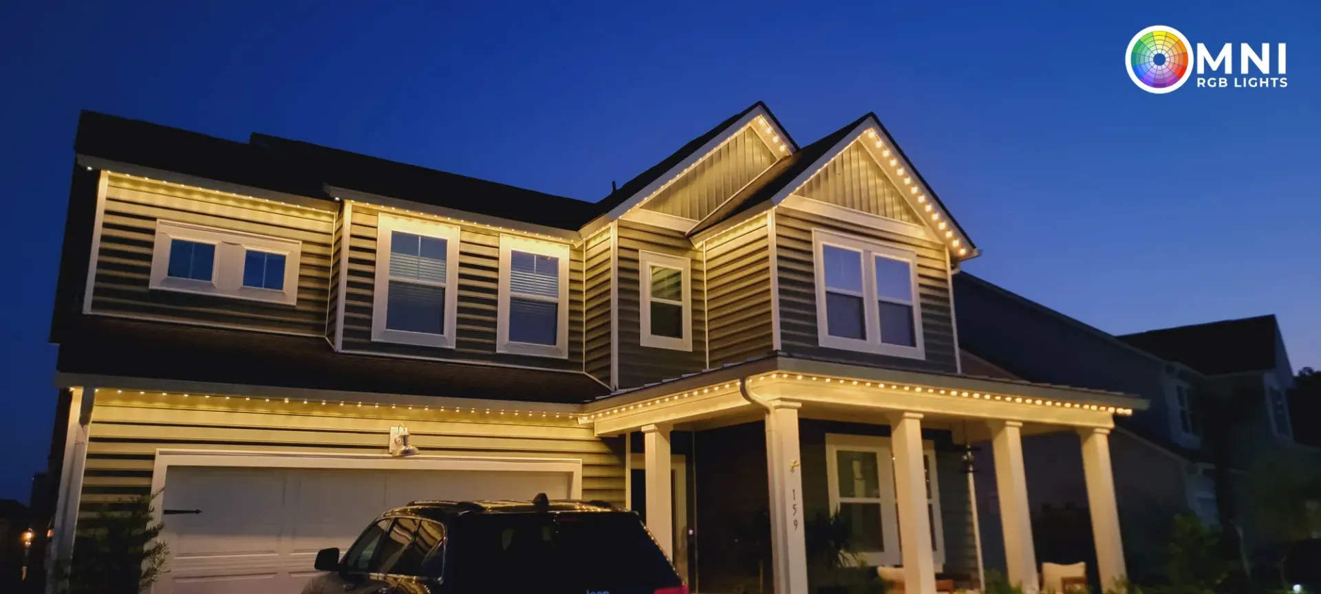 Two-story suburban house at dusk with warm exterior lights and a covered front porch