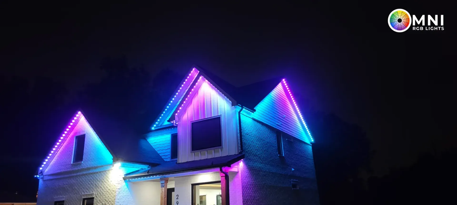 House roof outlined in blue, purple, and pink neon lights at night