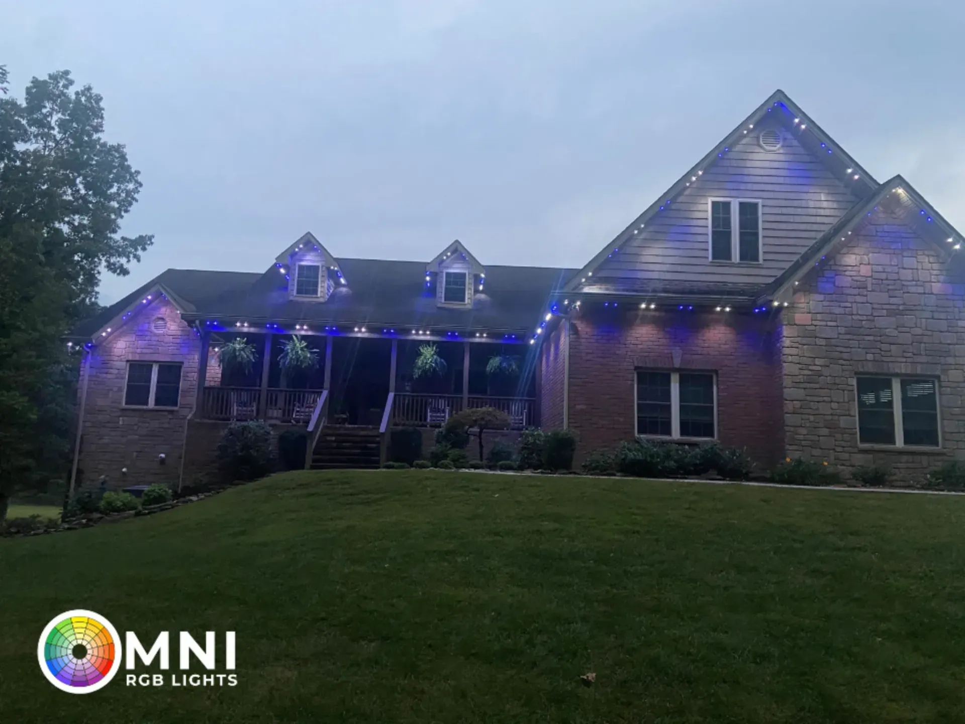 Suburban brick house at dusk with blue holiday lights across the roofline.