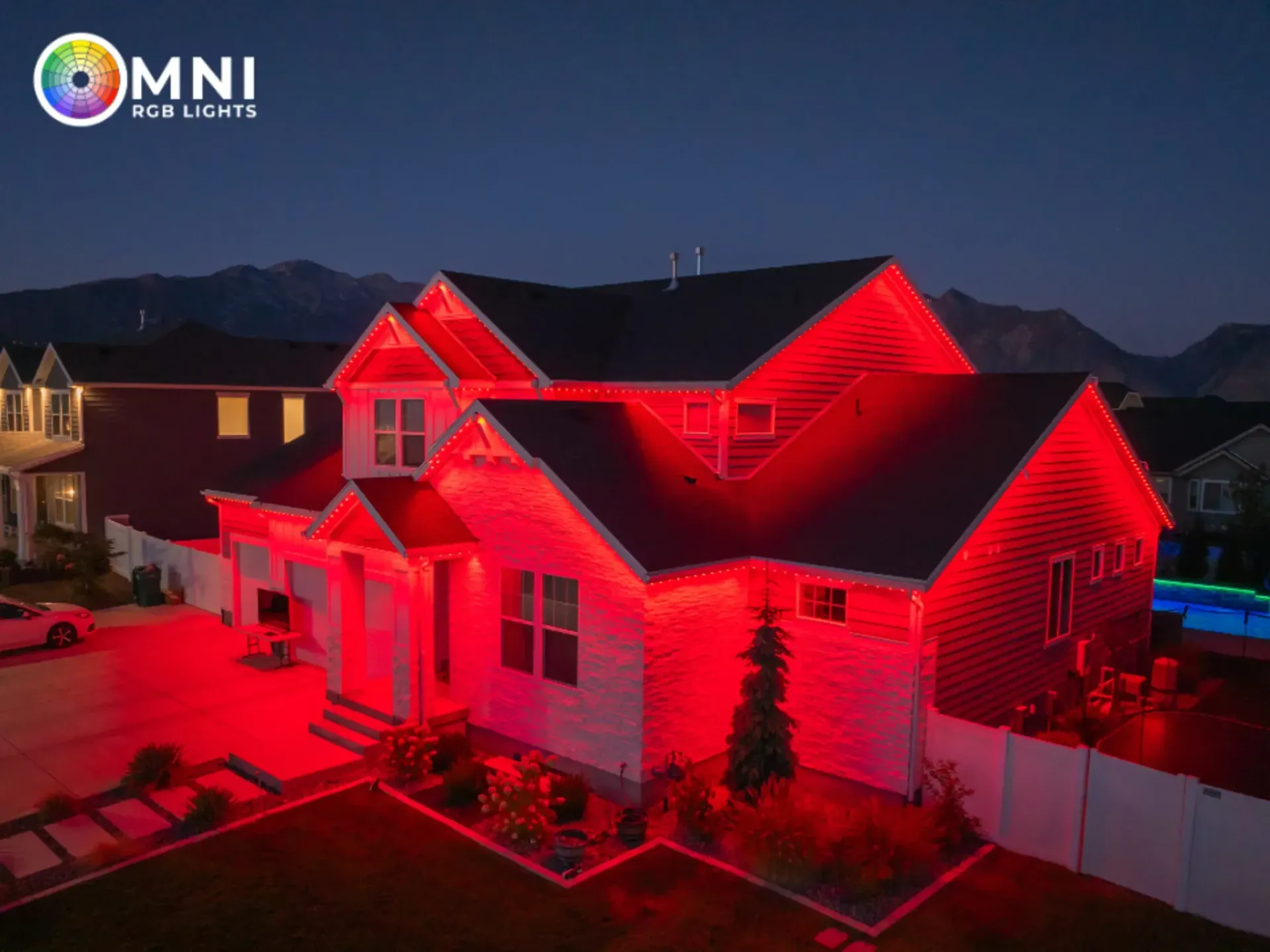 A house at night illuminated by vivid red lights, with a mountain backdrop and dark sky.