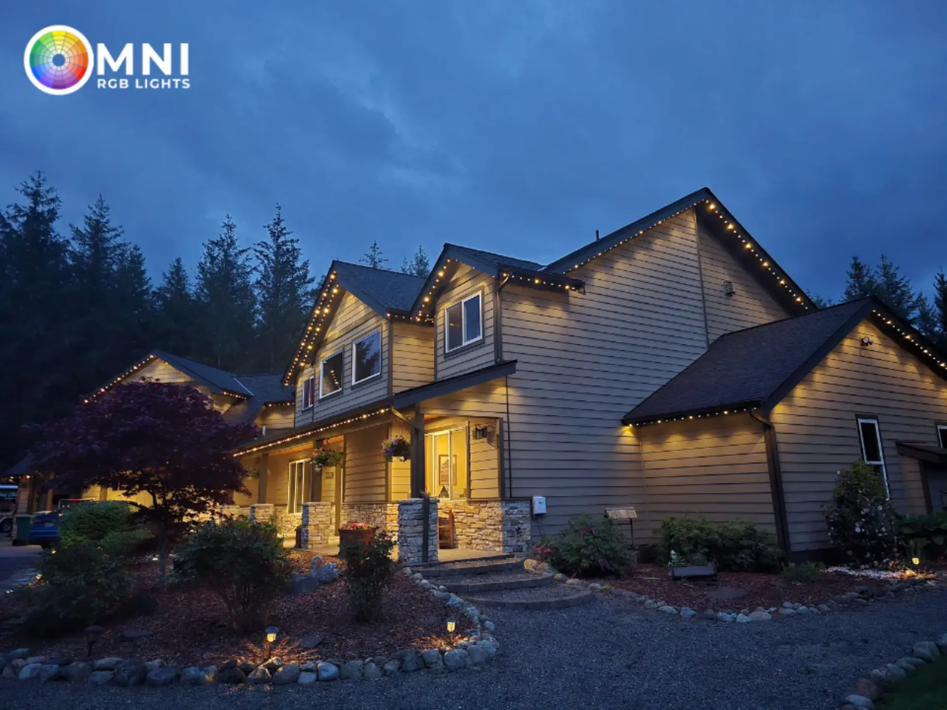 Warmly lit rustic cabin at dusk with stone path, surrounded by trees under a blue evening sky