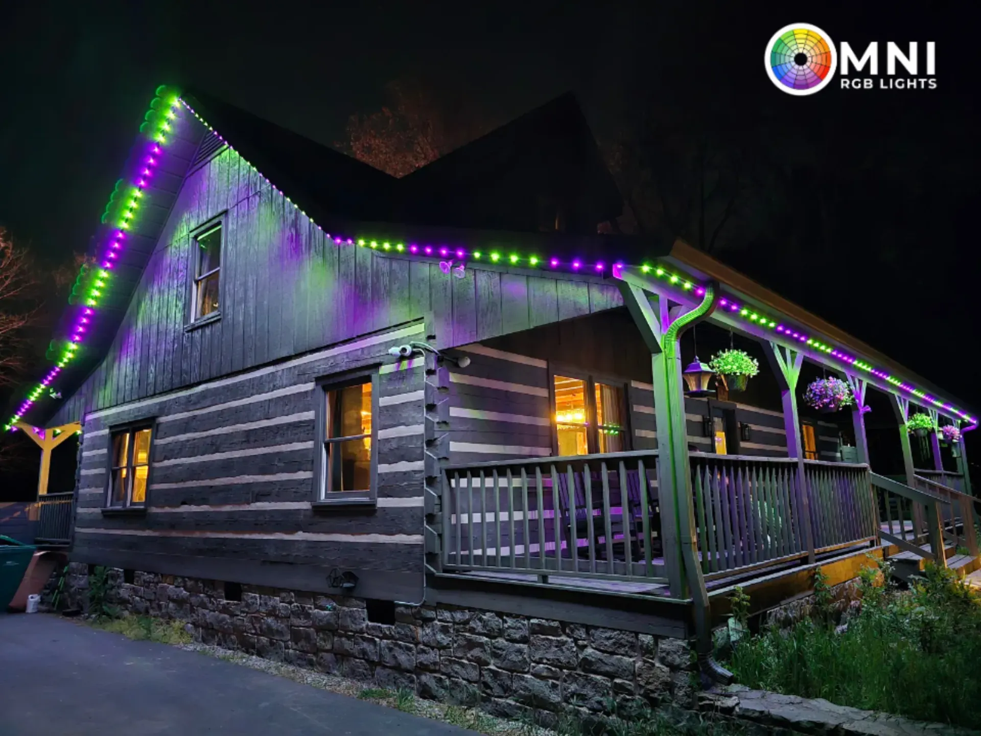 Log cabin at night with green and purple lights along the roof and porch