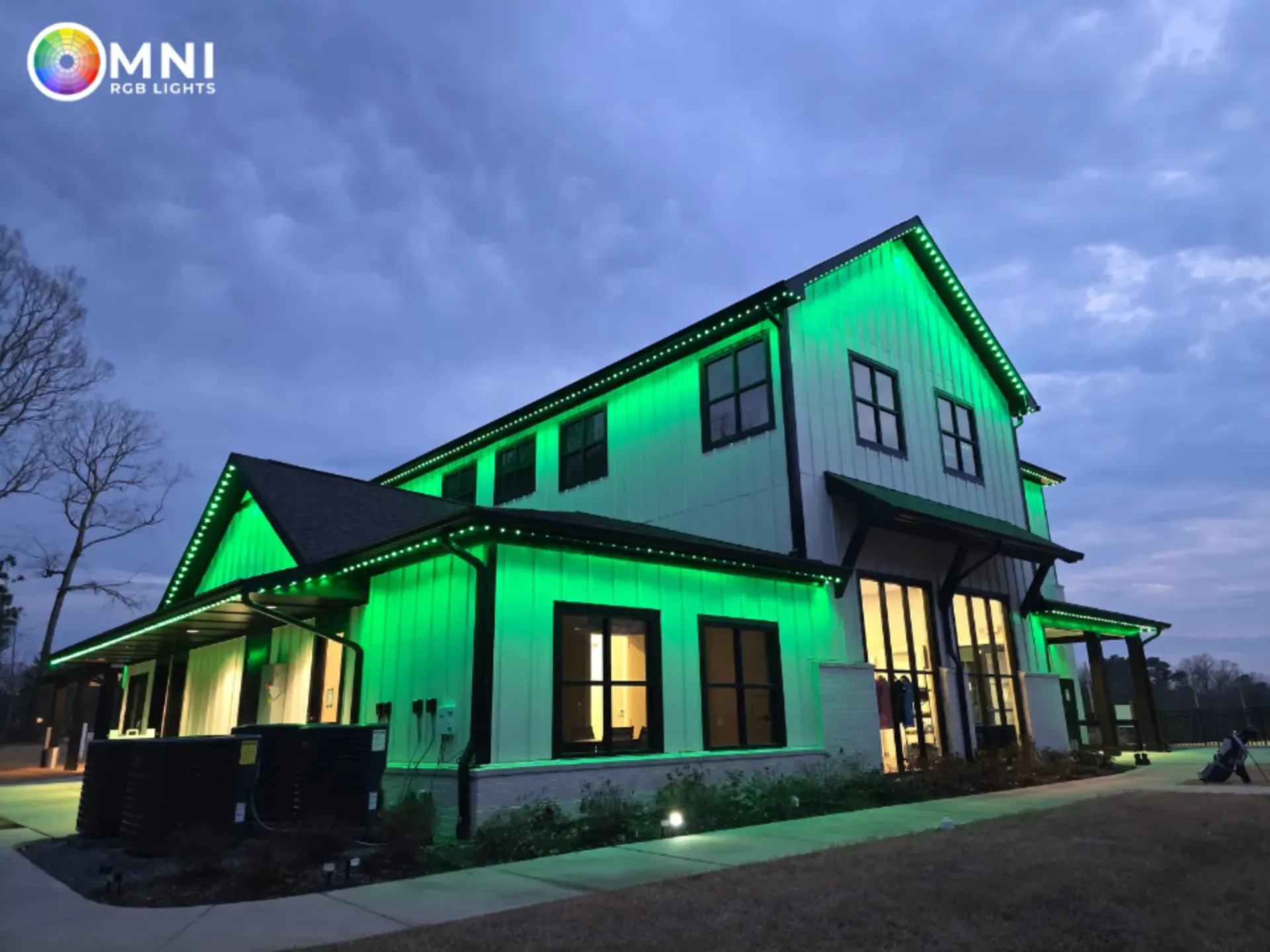 Modern house at dusk lit with green exterior lights under a cloudy sky