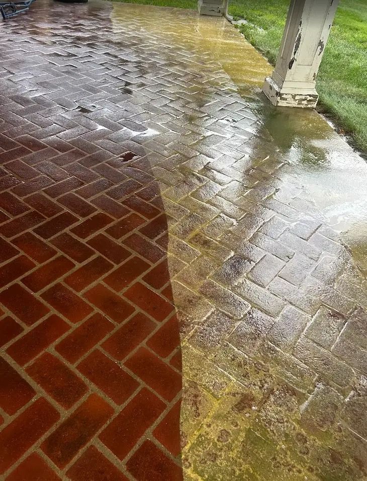 Wet brick and tile porch after rain, with puddles and reflections near a column.