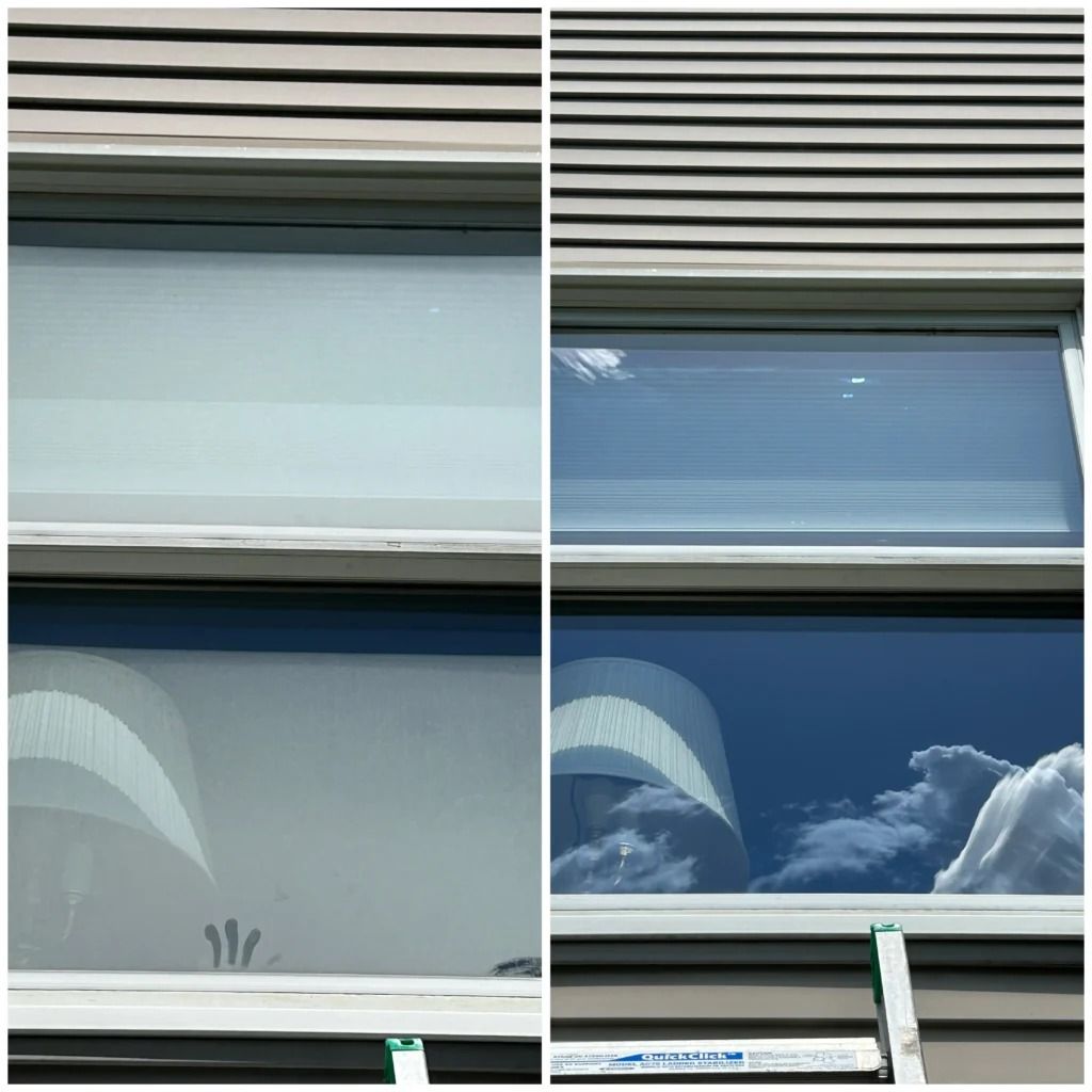 Two window panes with blinds, showing a bright sky and clouds reflected in the glass.