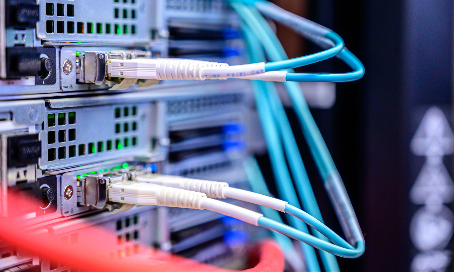 Network server ports with Ethernet cables plugged into a rack, lit in blue and red tones