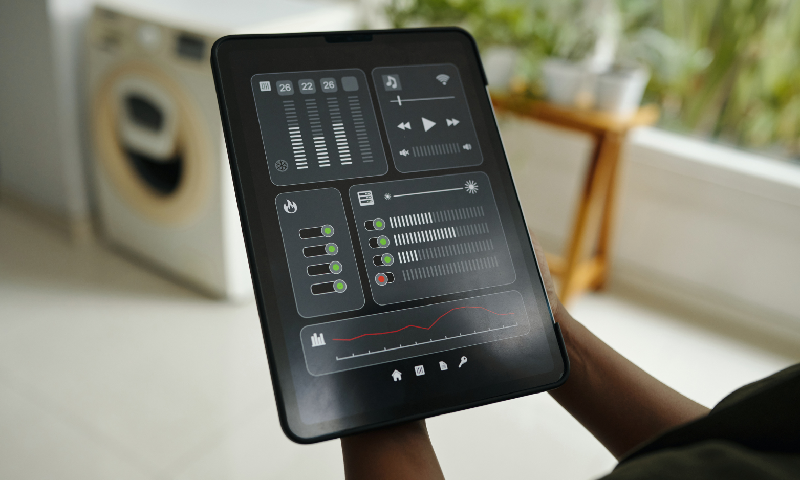 Tablet showing a dark dashboard app with charts and controls held in a person’s hand