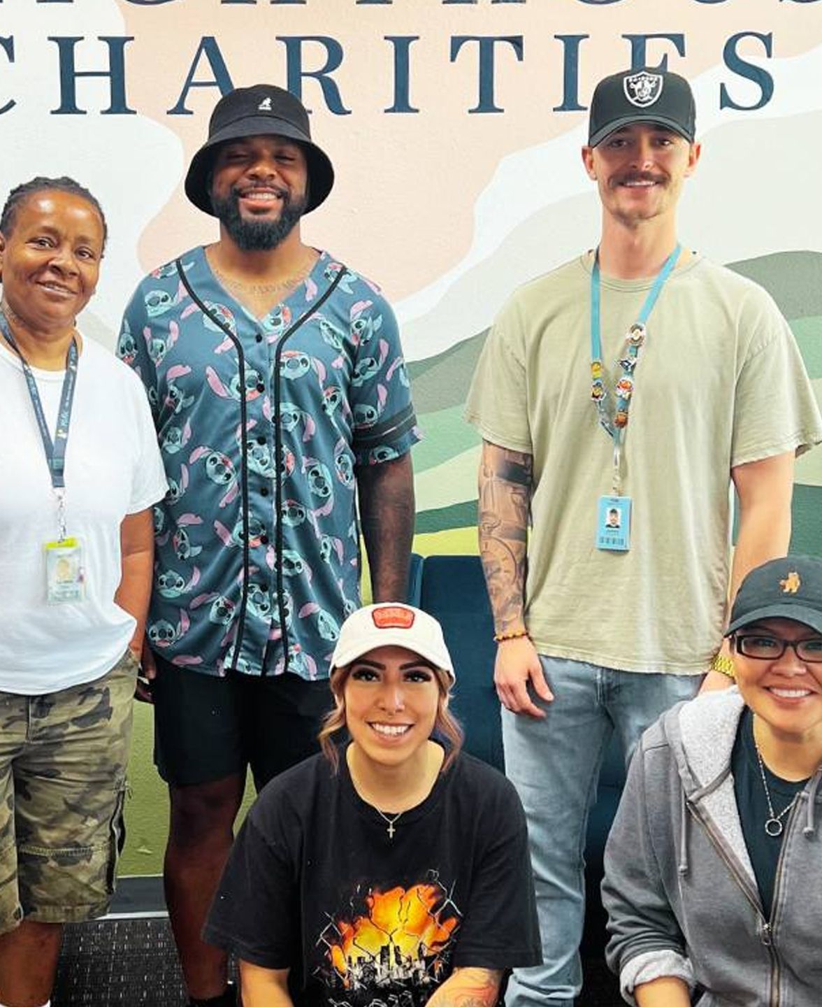 Group of people smiling, standing in front of a 