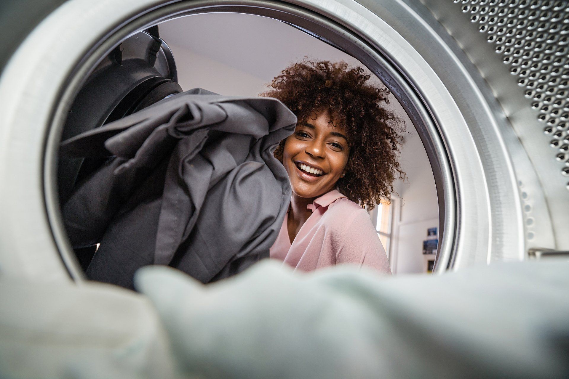African American woman holding a basket of clothes to be washed in an automatic laundry - Self-Service Laundry in Rochester, Minnesota