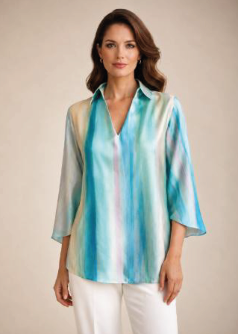 Mujer con blusa de seda a rayas azules y blancas y pantalones blancos sobre un fondo beige.