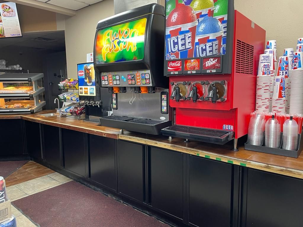 A row of soda machines are lined up on a counter in a restaurant.