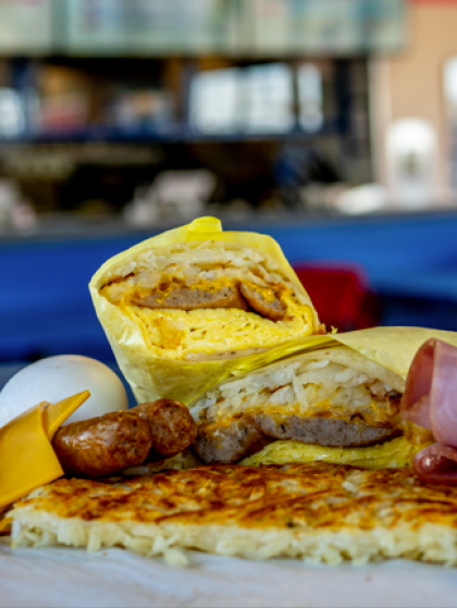 Assorted sandwiches and pastries on a table in a café, with a blurred indoor background