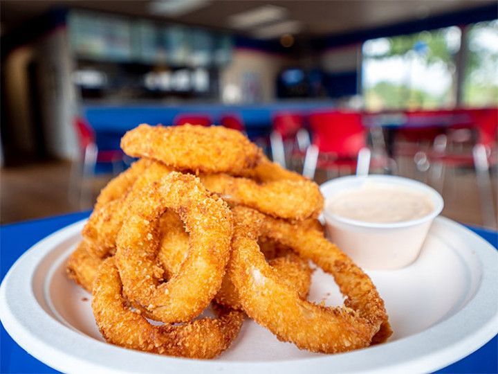 Plate of golden fried onion rings with dipping sauce on a restaurant table