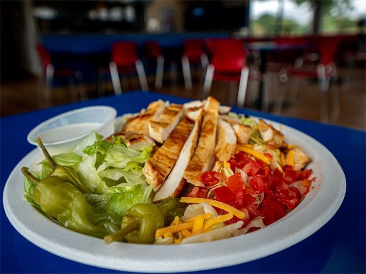 Plate of fajitas with lettuce, tomatoes, peppers, and tortillas on a blue table in a restaurant