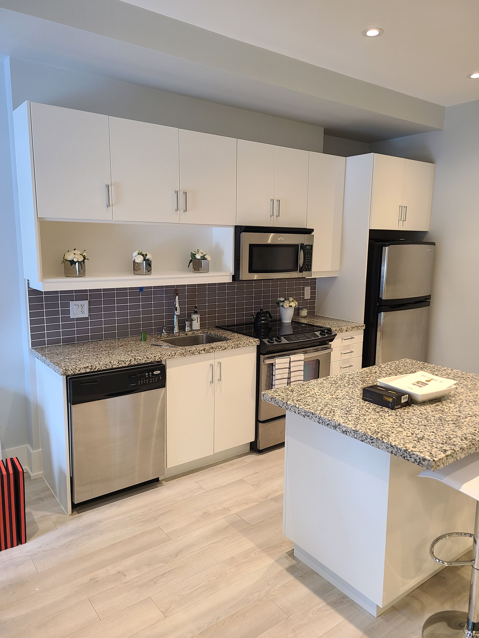 Kitchen with white cabinets, stainless steel appliances, and a granite countertop island.