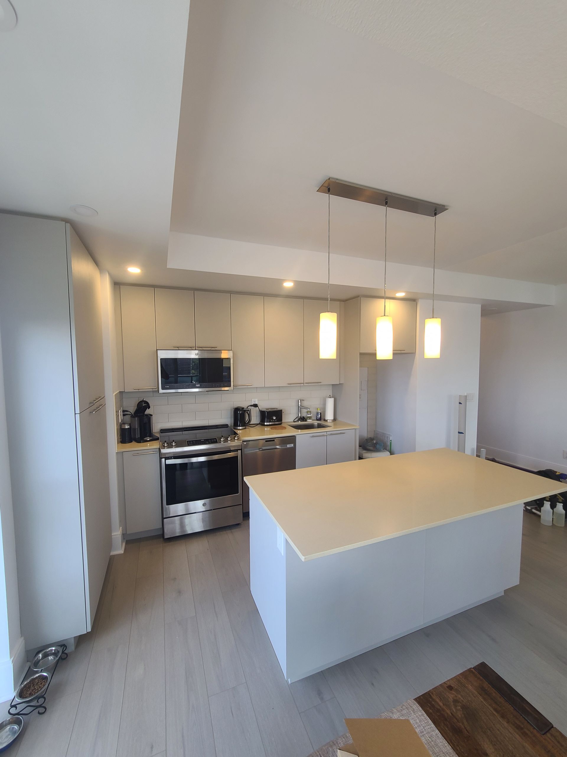 Newly renovated kitchen with gray cabinets, island, and stainless steel appliances; neutral tones.