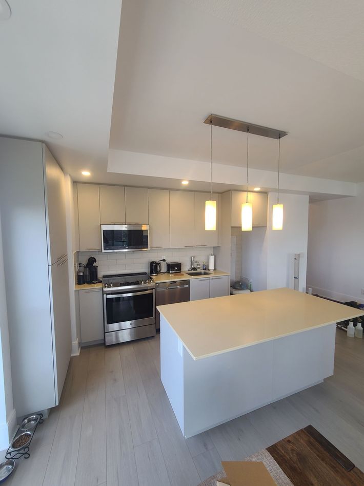 Newly renovated kitchen with gray cabinets, island, and stainless steel appliances; neutral tones.