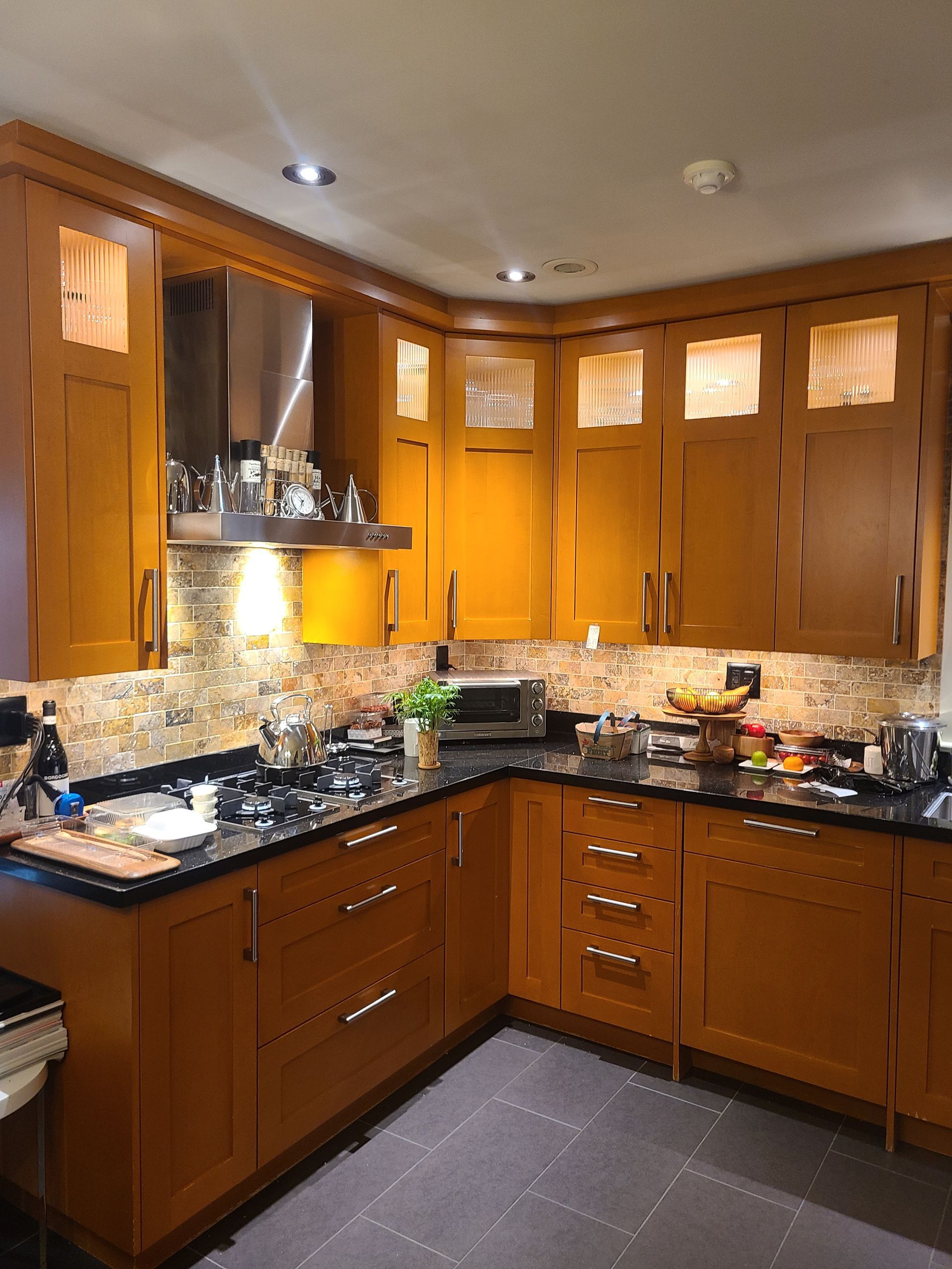 Kitchen with wood cabinets, dark countertops, and a tiled backsplash.