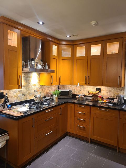 Kitchen with wood cabinets, dark countertops, and a tiled backsplash.