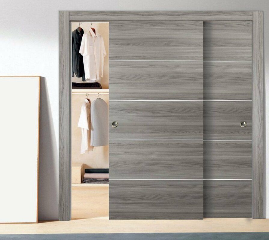 Gray wooden sliding closet doors, one partially open, revealing hanging clothes.