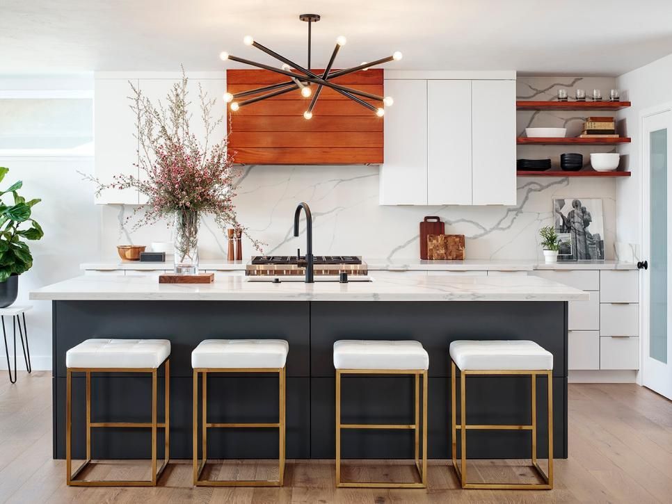 Modern kitchen with island, white countertops, dark cabinets, gold stools, and sputnik chandelier.