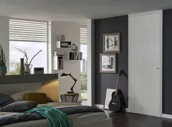 Bedroom with bed, windows, dark gray wall, white door, guitar.