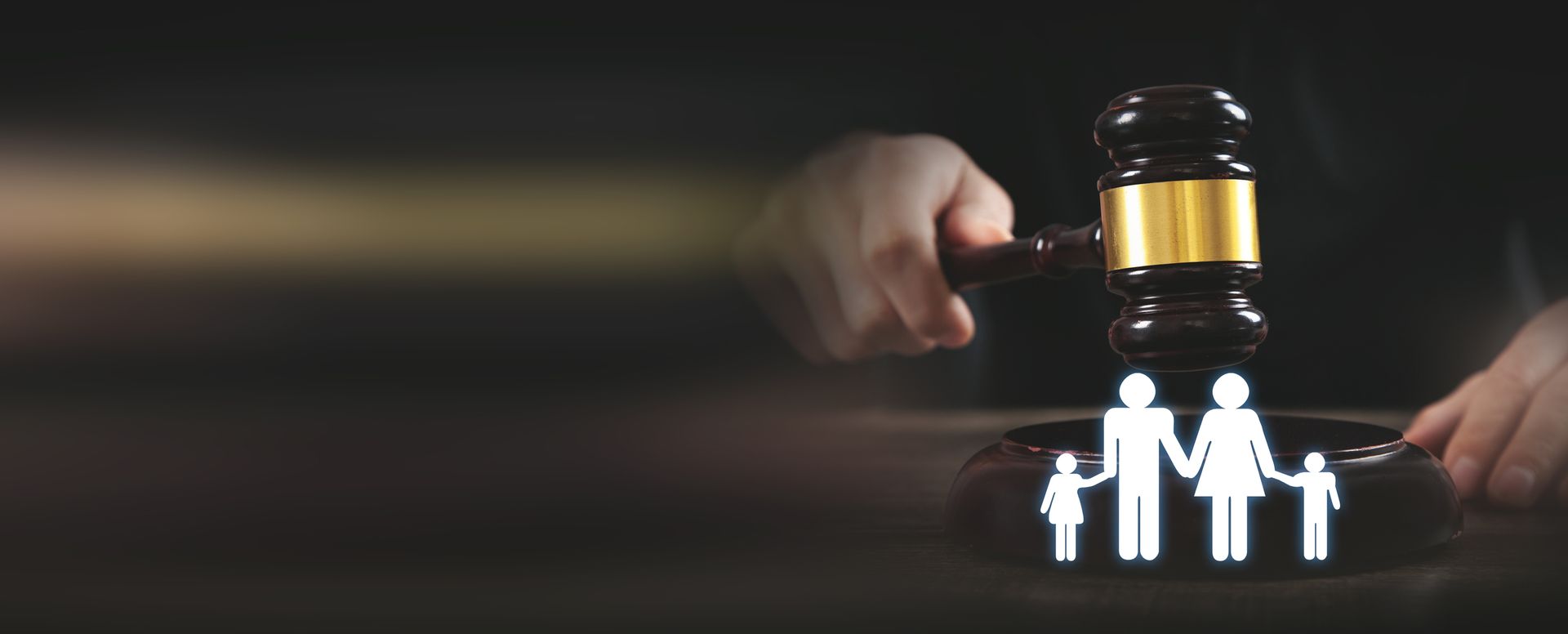 Un martelletto di legno poggia su un'icona bianca raffigurante una famiglia, simbolo del diritto di famiglia e dei procedimenti legali, su uno sfondo scuro.