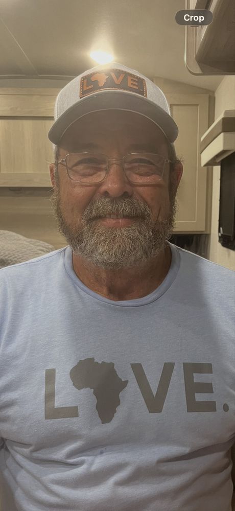 Smiling man in a cap and glasses wearing a light blue shirt with a “LOVE” graphic and Florida outline.