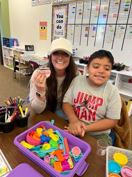 Teacher and student smiling at a table with colorful sensory toys in a classroom