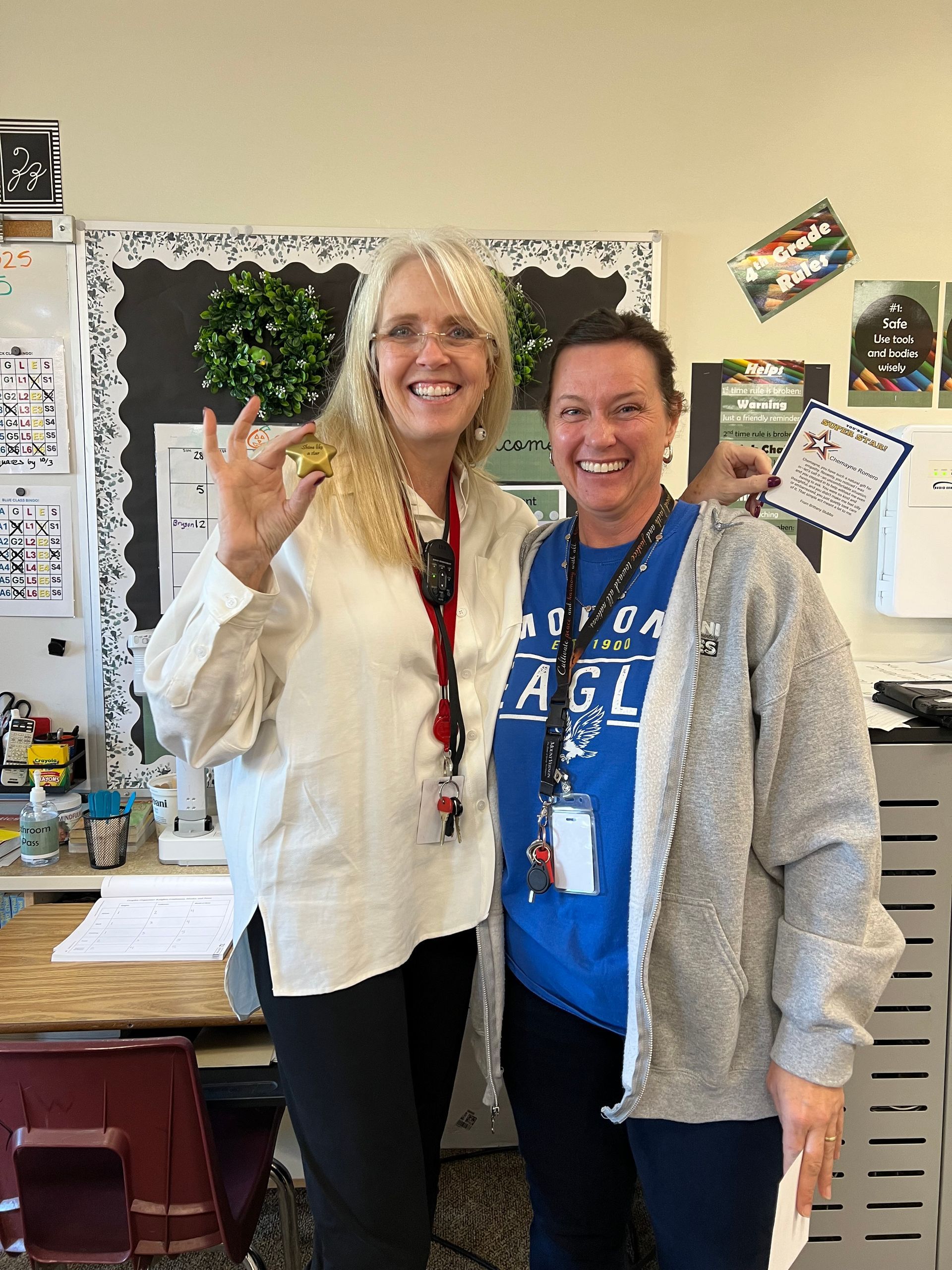 Two women are posing for a picture in a classroom.