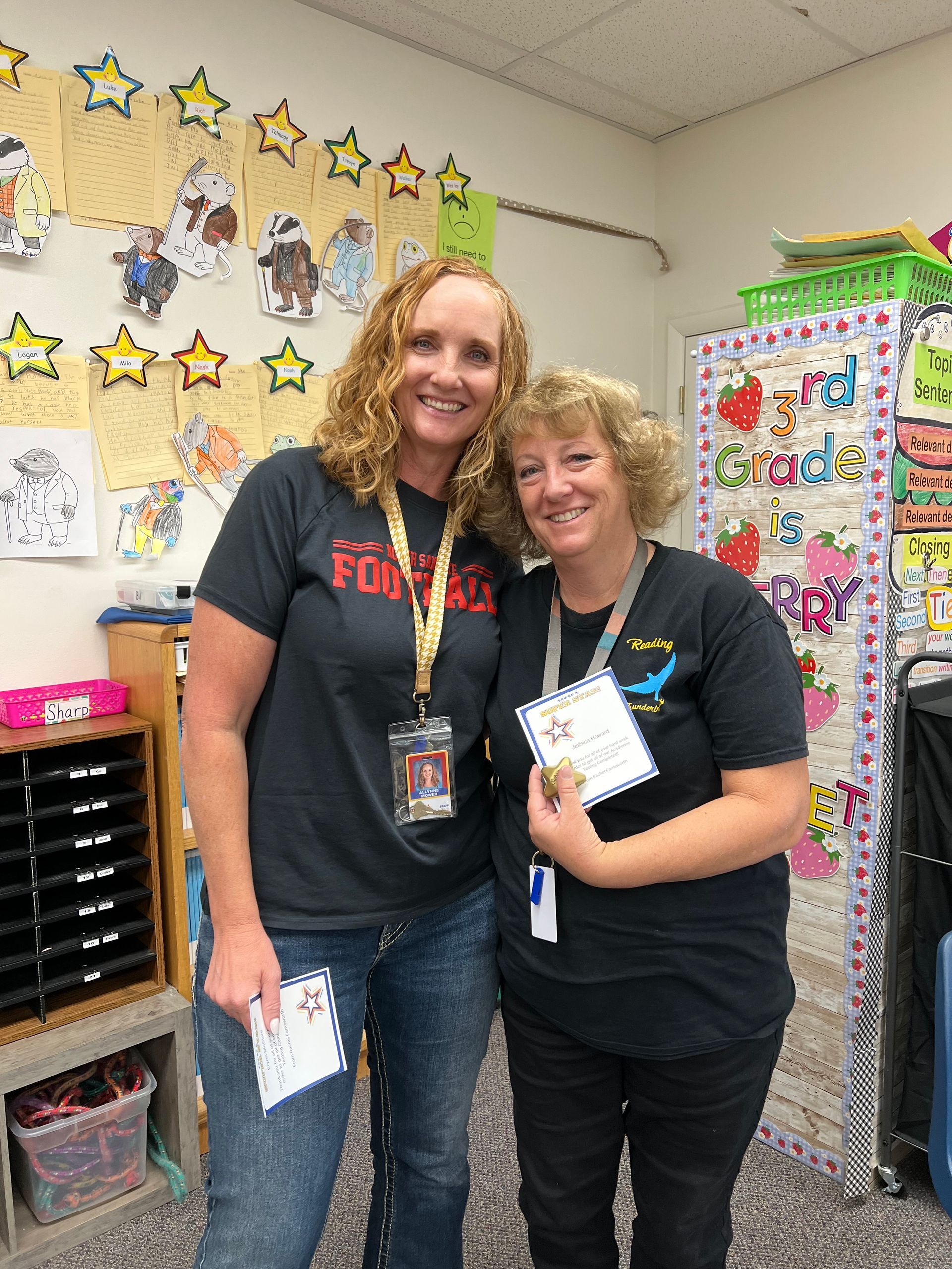 Two women are posing for a picture in a classroom.