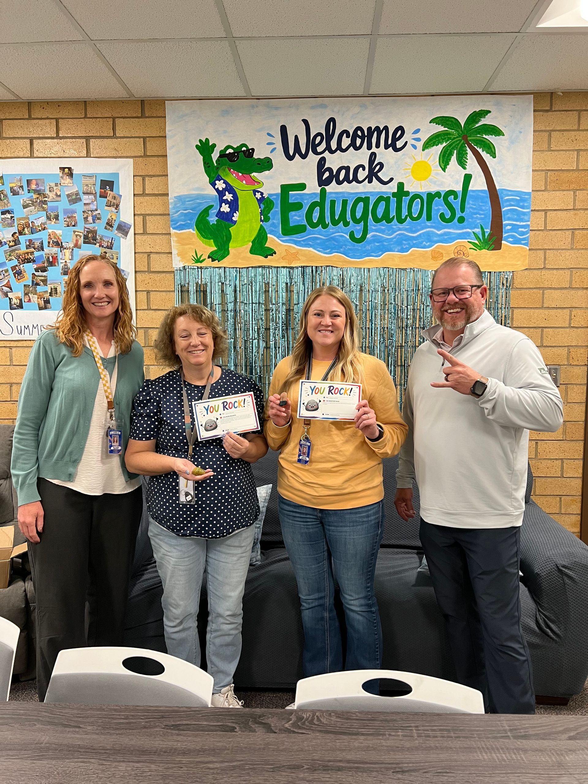 Four staff members holding gift cards pose under a “Welcome back Educators!” sign in a classroom.