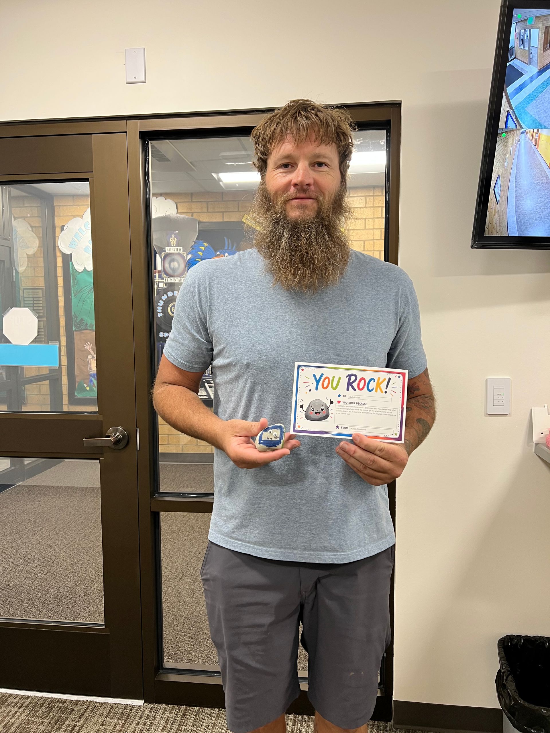 Man standing indoors holding a colorful children’s book in front of a doorway