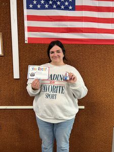 Person holding a certificate in front of an American flag and woven wall background