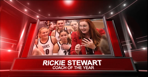 Rickie Stewart holding trophy with smiling team in red studio; banner reads “Coach of the Year”
