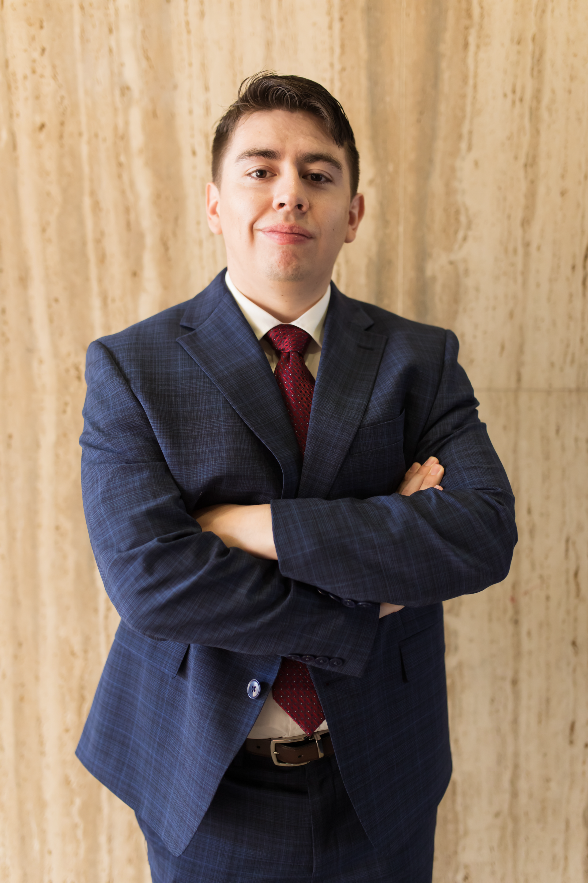 A man in a suit and tie is standing with his arms crossed.
