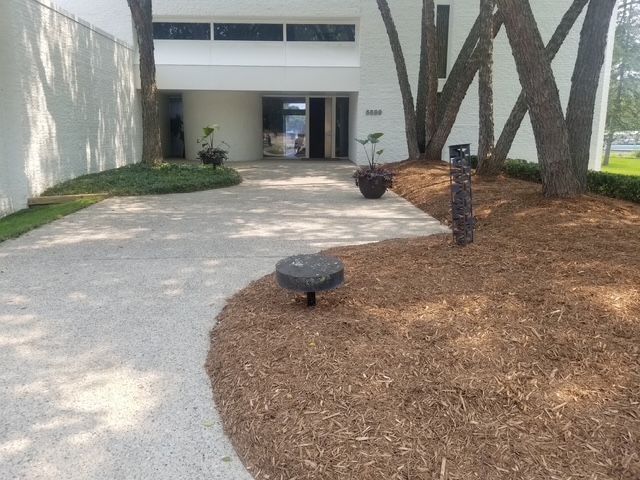 A white building with a walkway leading to it looking nice after landscaping