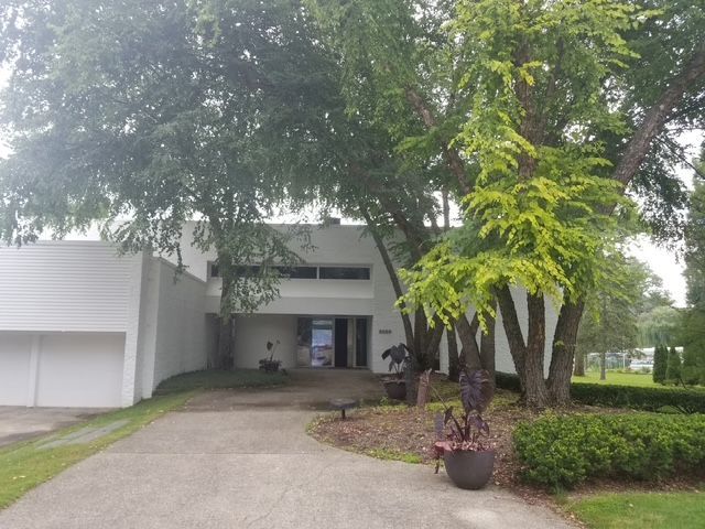 A white house with trees in front of prior to being landscaped