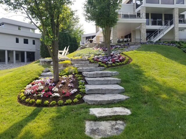 A lush green lawn with landscaped stone slab stairs leading up to a large modern house.