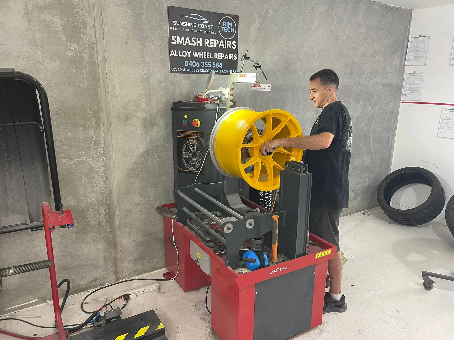 Man working on a yellow car wheel with a machine in a repair shop. — Coolum Smash Repairs in Coolum Beach, QLD